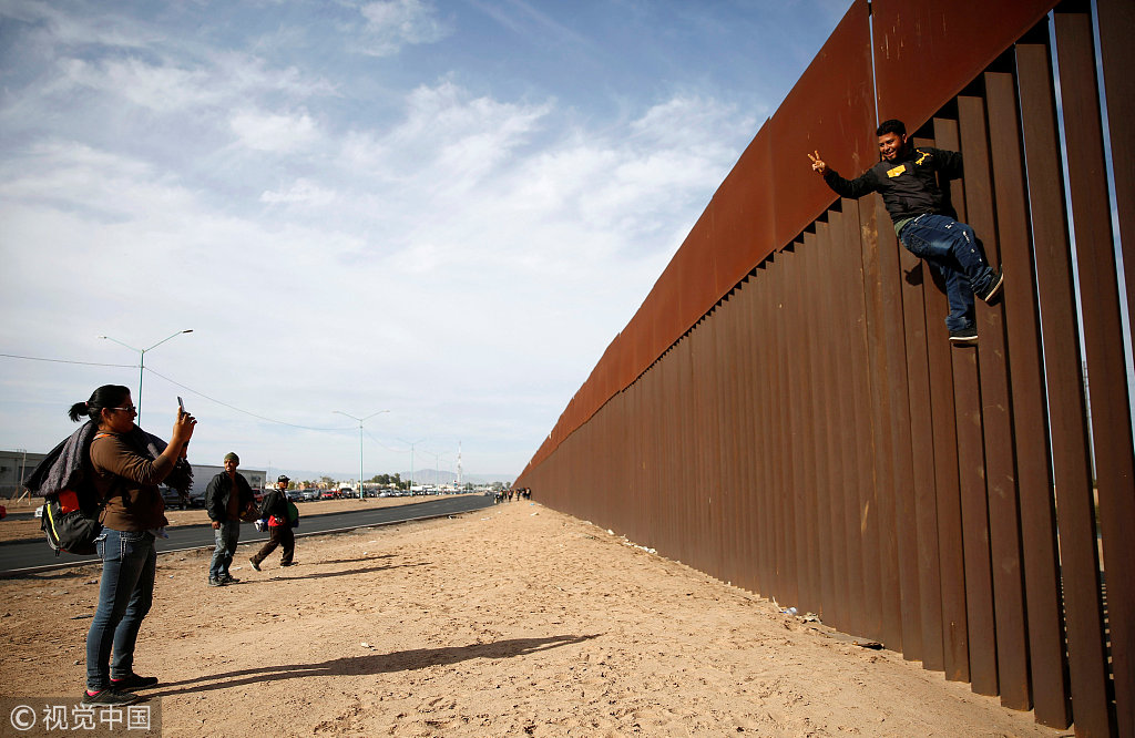大批中美洲移民持续抵达美墨边境 徒手攀爬边境隔离墙