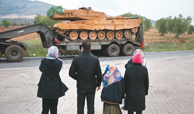 图为1月21日，在土耳其与叙利亚接壤的基利斯城郊外，当地居民观看军车运送坦克。.jpg