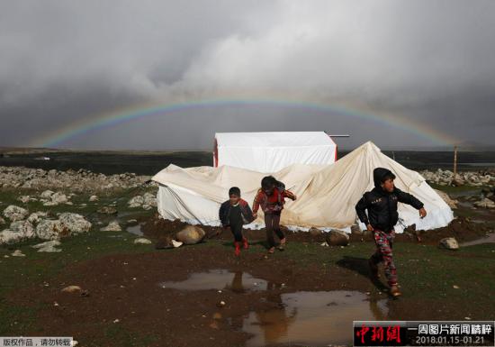 当地时间1月19日，叙利亚南部城市库奈特拉的一个难民营上空出现彩虹，孩子们在泥泞中奔跑玩耍。