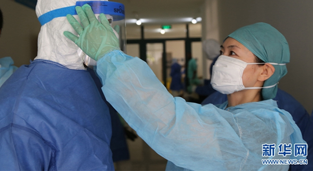 在援塞抗击埃博拉时，王新华检查穿戴防护用品。