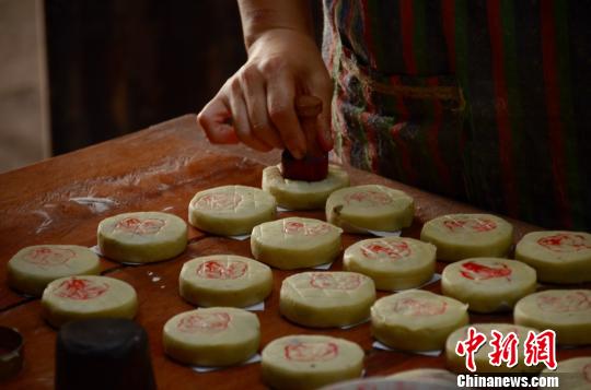 糕点师傅向压模定型好的月饼上盖章，标注其馅料成分 余皓 摄