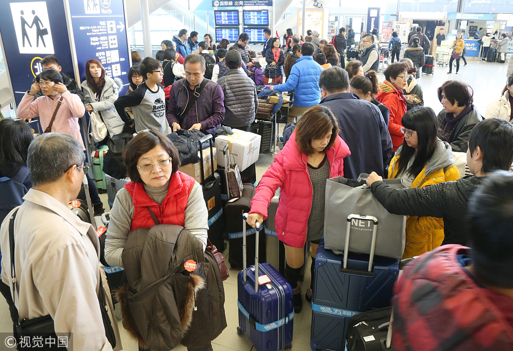 在大阪机场拎着大包小包准备登机的中国游客