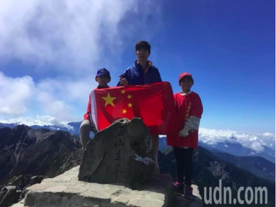  郑建炘与儿子持五星红旗登顶台湾第一高峰玉山主峰。（来源：台湾《联合报》）