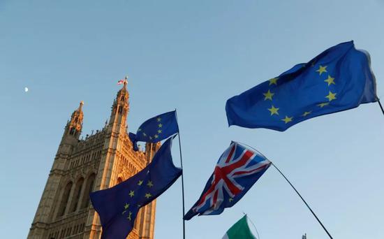  2月14日，在英国伦敦，人们在议会大厦外手举英国与欧盟旗帜。新华社记者韩岩摄
