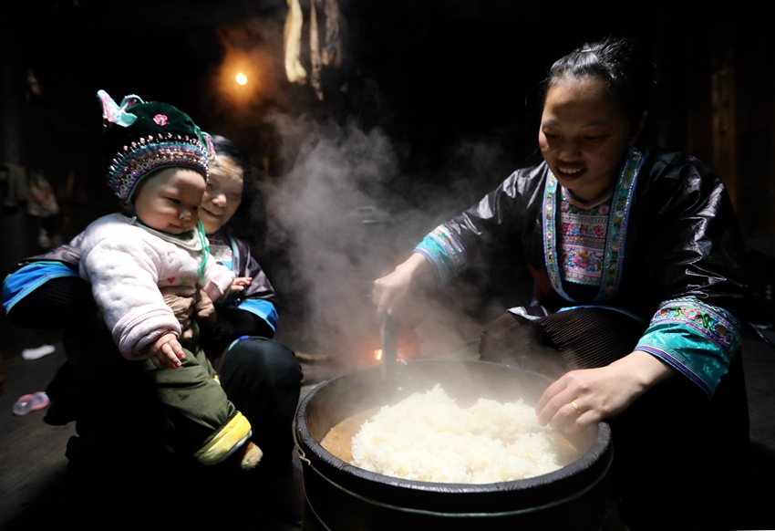 12  3月1日，位于桂黔交界的广西融水苗族自治县杆洞乡尧告苗寨，苗族女青年梁妤和家人把蒸好的糯米饭倒出准备午餐。_副本.jpg