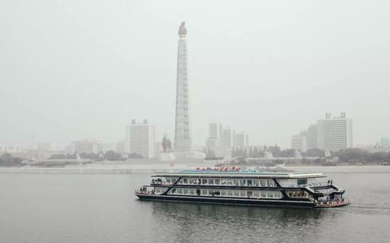 这是2015年10月18日拍摄的从“彩虹”号一层船舷边眺望主体思想塔和大同江上的游船。新华社记者朱龙川摄