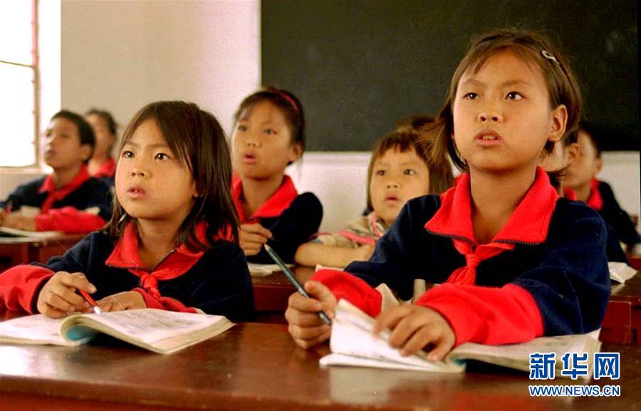 苦聪姐妹张民勒（前右，时年10岁）和张民松（前左，时年8岁）和同学们在云南省者米乡下纳咪小学内上课（资料照片）。新华社记者 蔺以光 摄