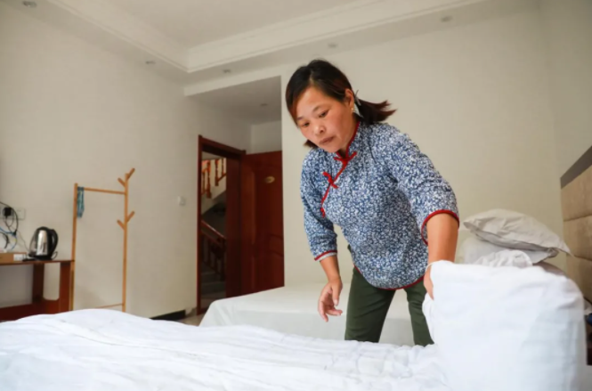 肖细雨在自己一手创办的农家乐为游客整理房间。张俊摄