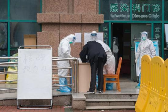  2月7日，在武汉市中心医院后湖院区核酸检测预约处，工作人员为一名男子登记。新华社记者 才扬 摄