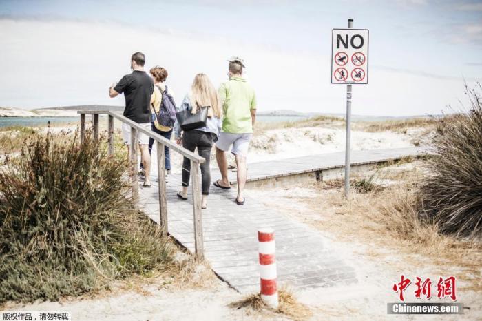 资料图:2020年12月29日,南非兰格班,几名游客在海滩前观望。 点击进入下一页