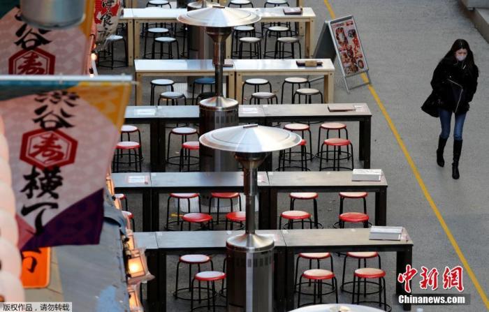 当地时间1月7日，日本东京，一名路人路过空荡的户外餐馆。