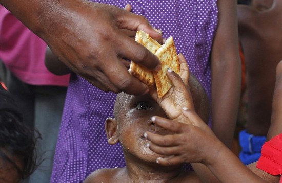 一位饥饿的孩子注视着志愿者递来的食物.