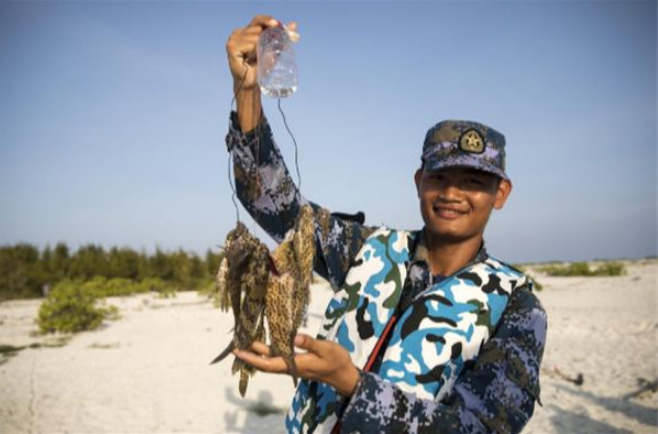 中建岛守备营战士王国达在野外生存训练中展示海里钓到