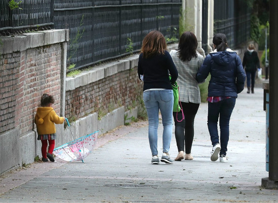 一名儿童在大人陪伴下散步（图源：《国家报》）