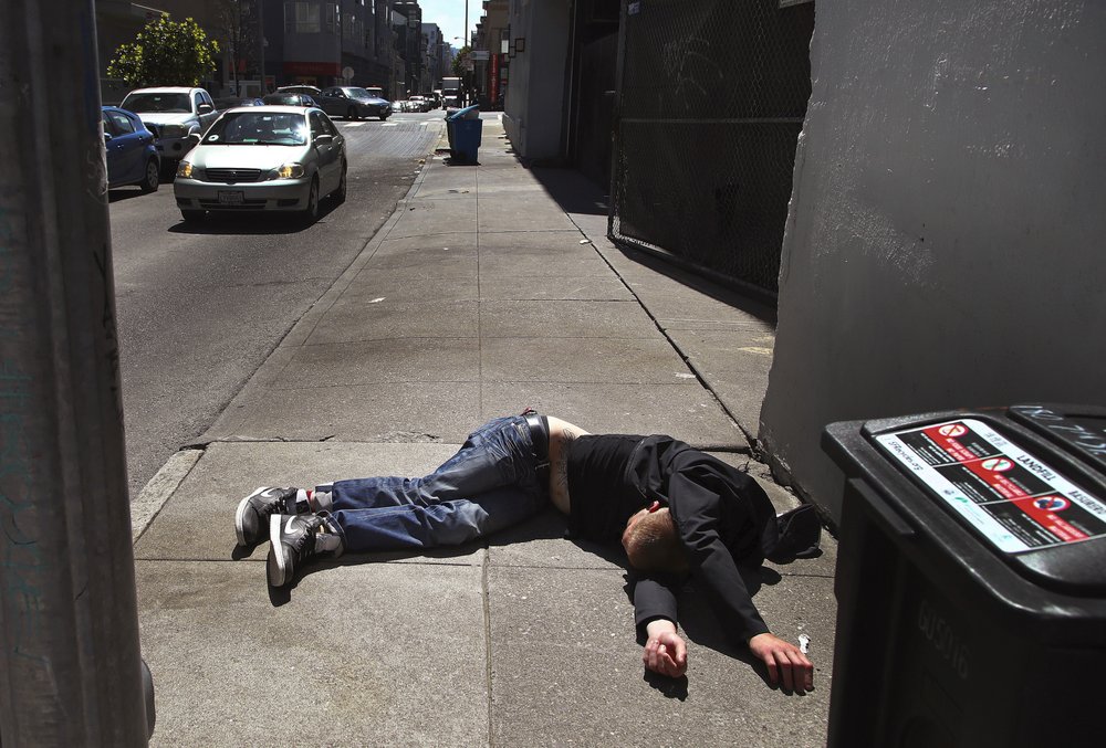 资料图：一男子躺在垃圾桶旁边的人行道上。（美联社）
