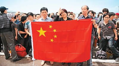 图为2010年6月，在吉尔吉斯斯坦奥什国际机场，杨彩平（前排中）和等候撤侨包机的侨胞手持中国国旗的合影。受访者供图