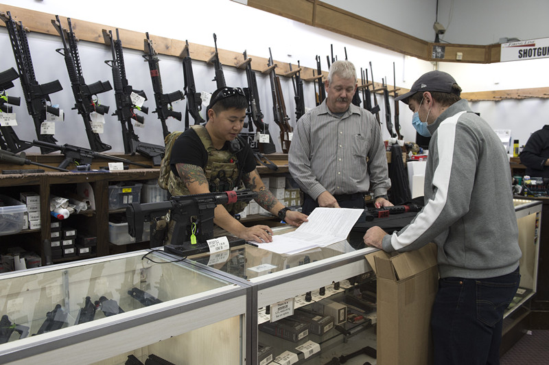 资料图：美国枪店工作人员为顾客选购弹药。
