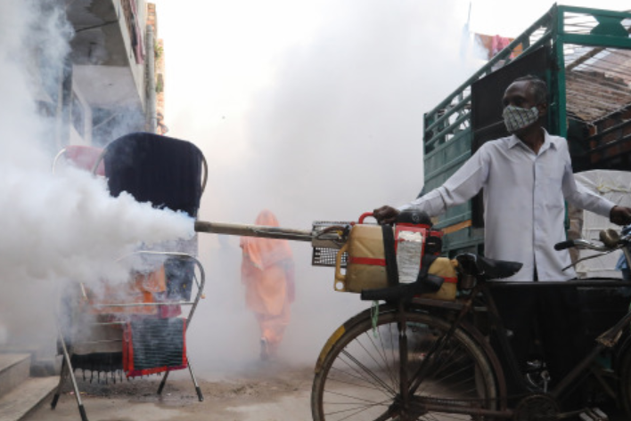 印度工作人员在街头进行熏蒸消毒。