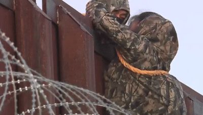 美墨边境惊险一幕：非法移民穿迷彩服爬墙 绑绳索穿铁丝网到美国